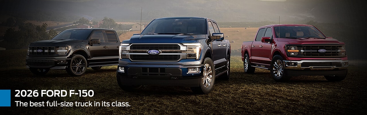 Three 2026 Ford F-150 trucks in black, blue, and red parked in a rural landscape.